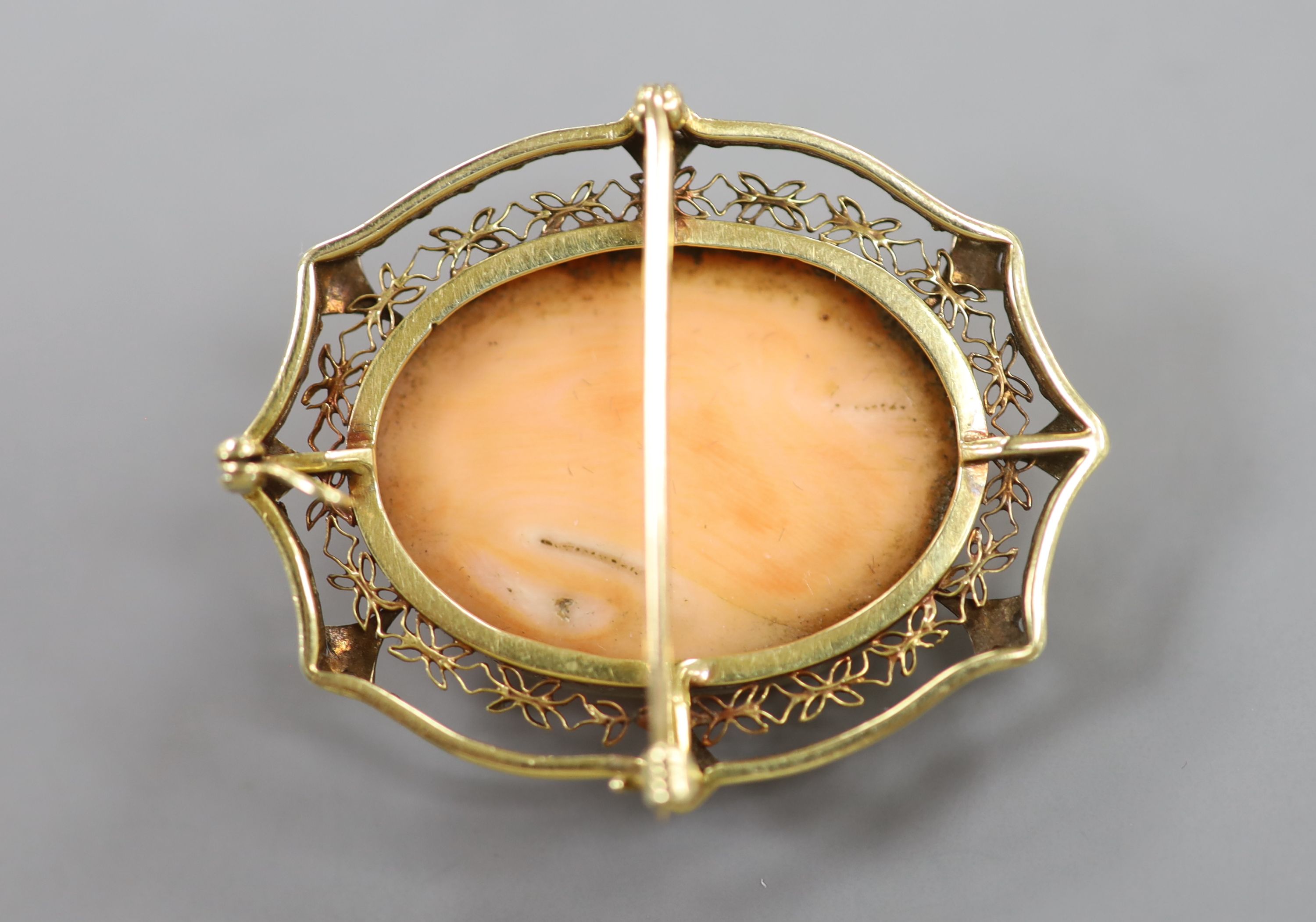 An early 20th century yellow and white metal mounted oval coral pendant brooch, carved with the bust of a lady to sinister